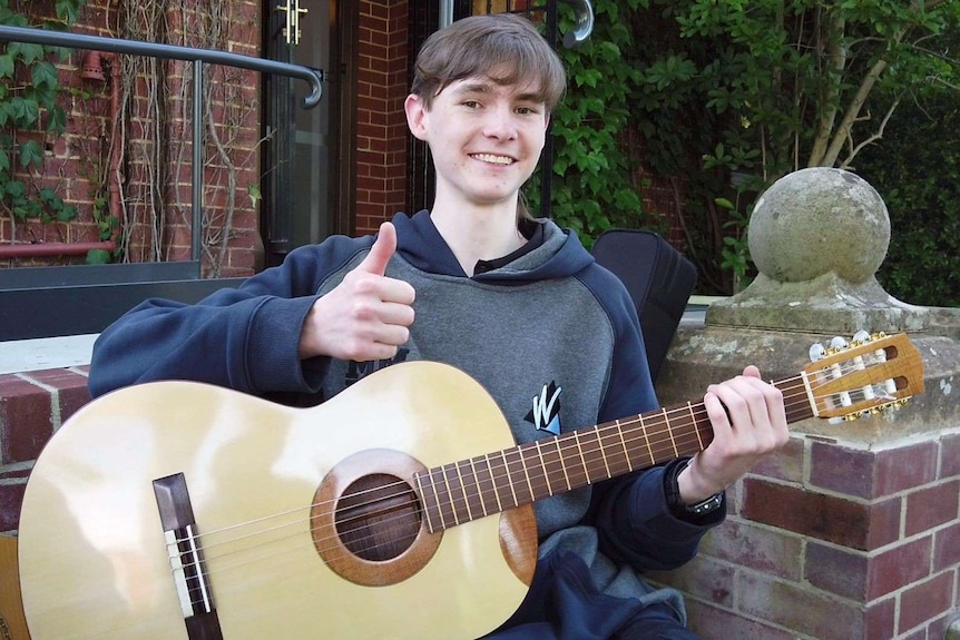 Tom Dunlop gives the thumbs up while holding a new guitar.