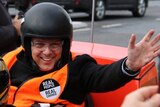 Nick Xenophon waves as he turns up on a motorbike to vote