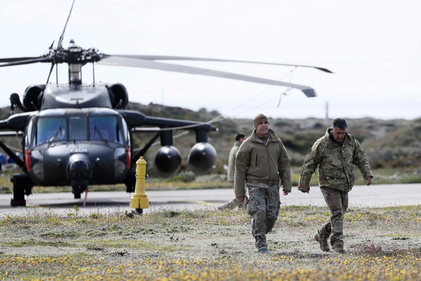 Two military people walk away from a helicopter