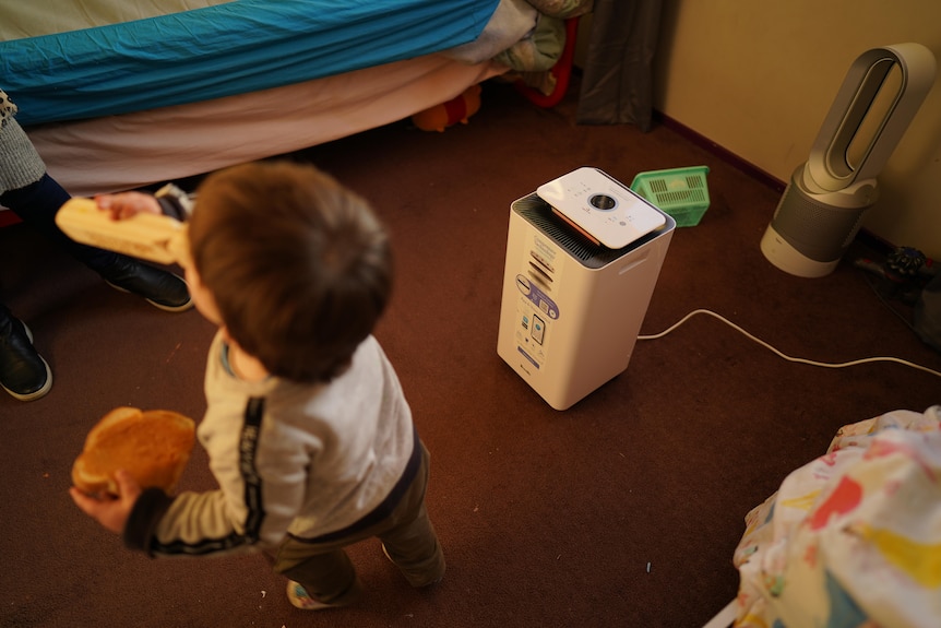 A child stands next to an electronic device.