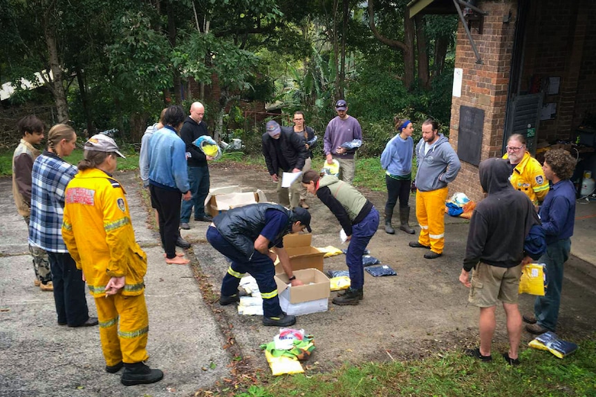 Group of new RFS volunteers in circle as others get uniforms and PPE equipment out of boxes.