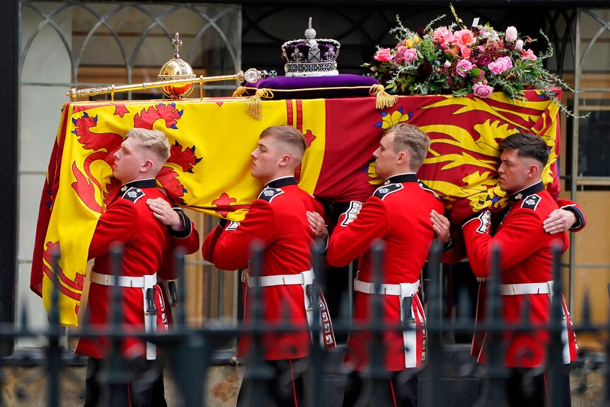 棺材持有人携带女王的棺材，棺材上覆盖着红色和黄色的皇家旗帜。