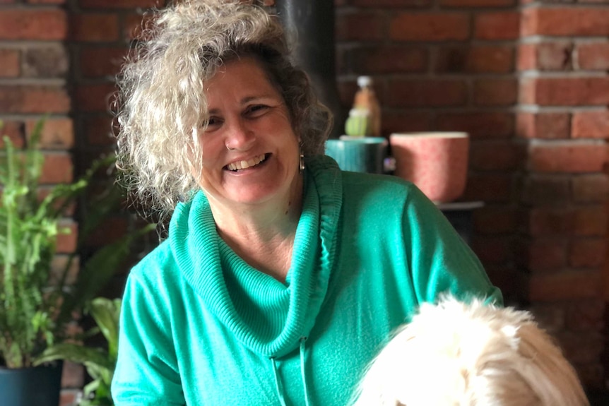 A woman laughs while holding her dog