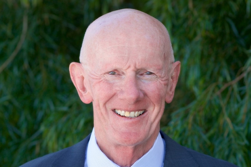 A bald elderly man wearing a suit and tie 