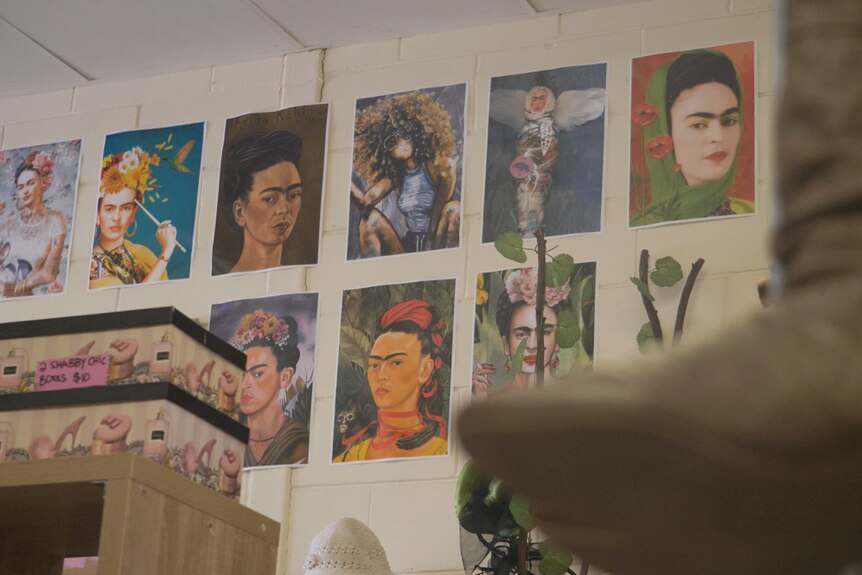 Self-portraits of Frida Kahlo line a wall