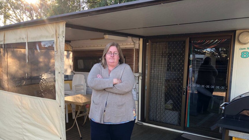 Permanent caravan tenant Linda Shinner stands with her arms crossed in front of her 40-year-old caravan.