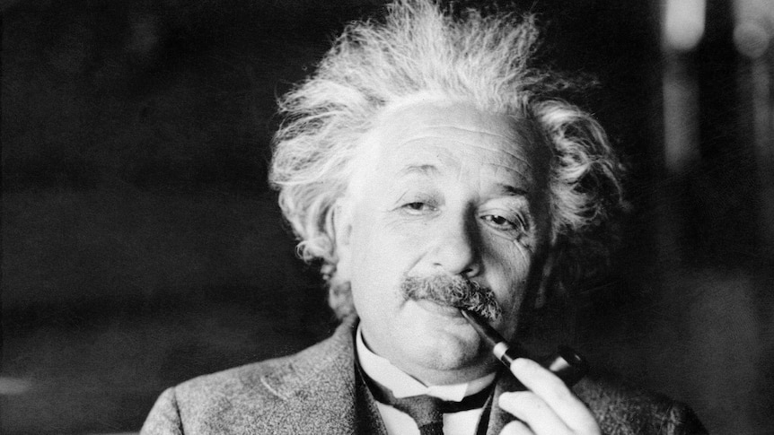 Albert Einstein smokes a pipe with a relaxed, thoughtful expression on his face.