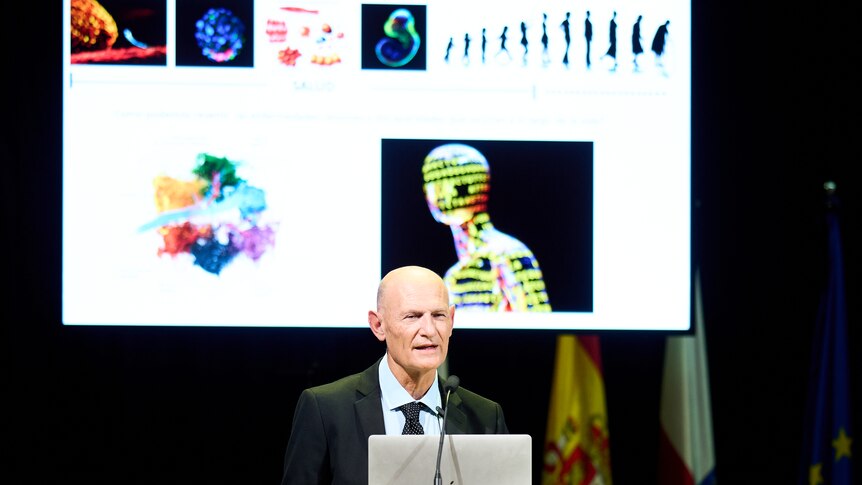 Spanish scientist Juan Carlos Izpisua Belmonte speaking at a conference with projected images behind him