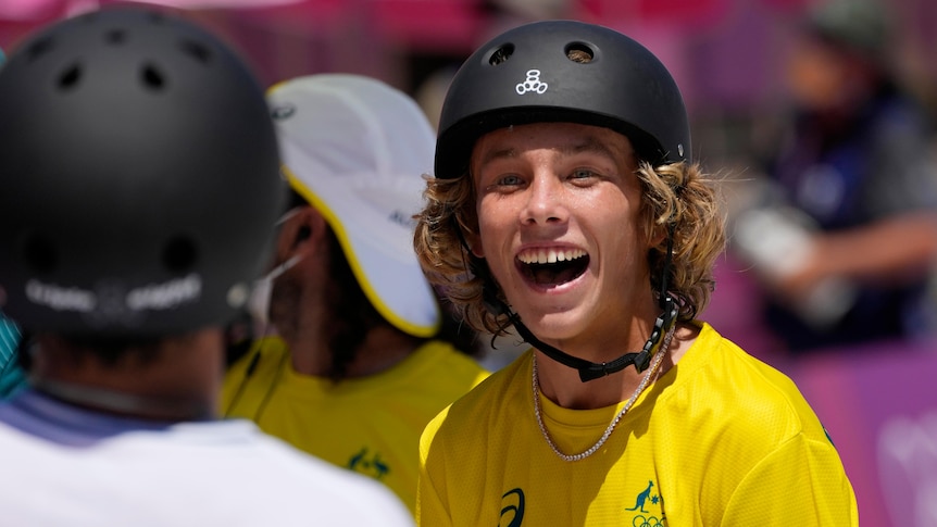 An Australian skateboarder stands wide-eyed with a huge smile as he leads the Olympic men's park competition.