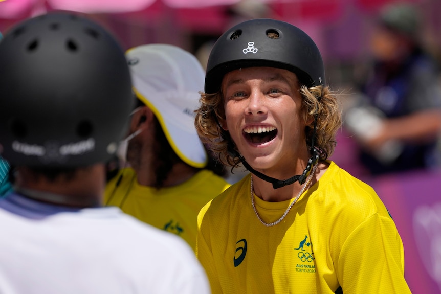 An Australian skateboarder stands wide-eyed with a huge smile as he leads the Olympic men's park competition.