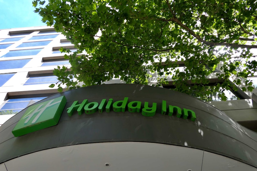 A view of a Holiday Inn motel from the ground looking up at the sky.