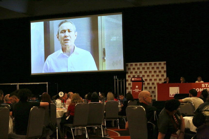 Roger Cook speaks on a big screen in front of party faithful at the state Labor conference