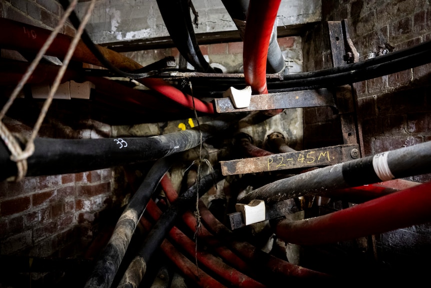 The tunnel's walls are lined with red and black high-voltage power cables. 