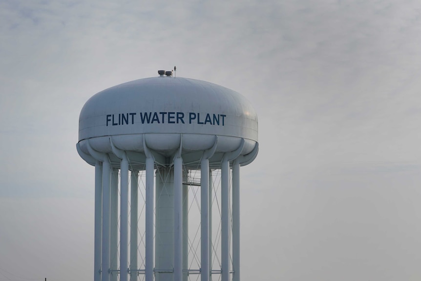 A high white water tower is panted with the words Flint Water Plant.