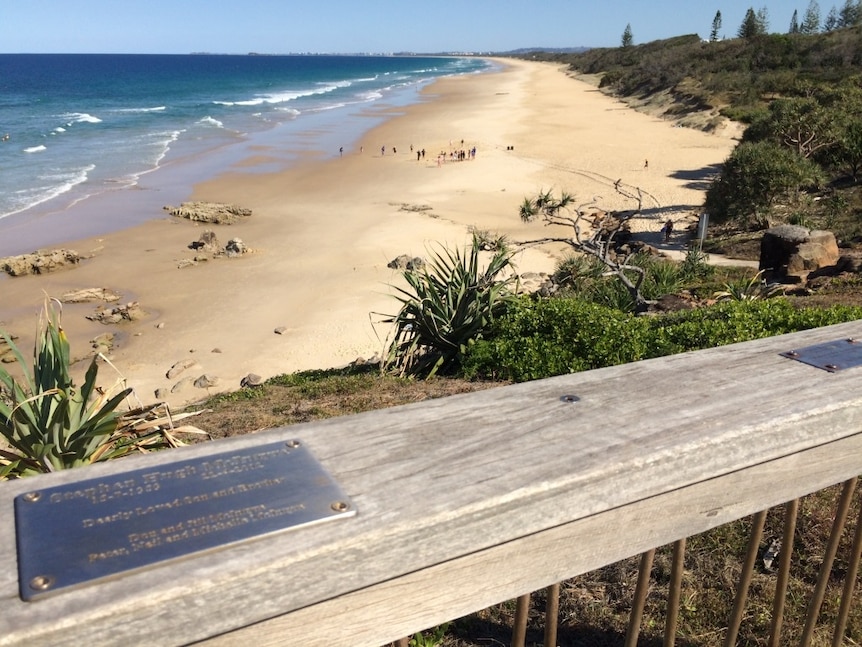 Metal plaques on barrier of lookout that's overlooking a beach