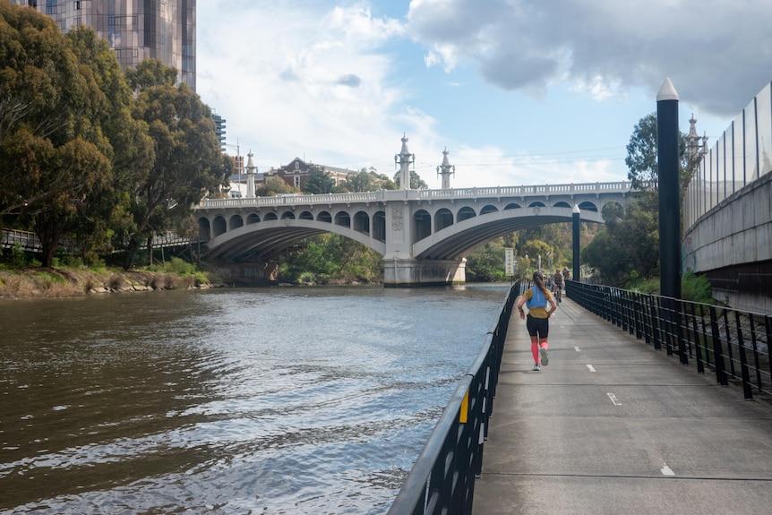 A Melbourne bridge over the Yarra River with a woman running in the distance.