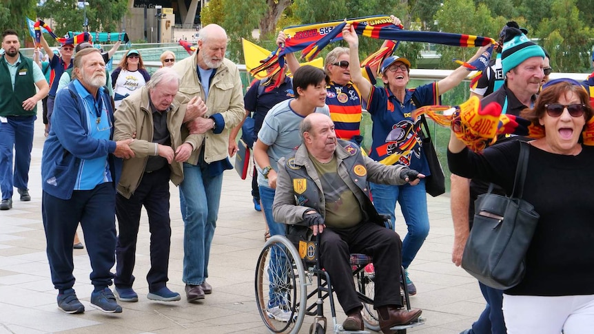 Roy Billing, Jack Thompson, James Cromwell, Dennis Waterman and Zachary Wan are in a crowd leaving an Adelaide AFL match.