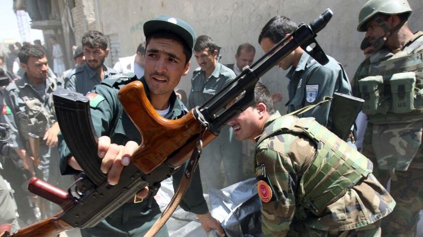 Afghan policemen carry the bodies of two gunmen killed after a shootout in Kabul