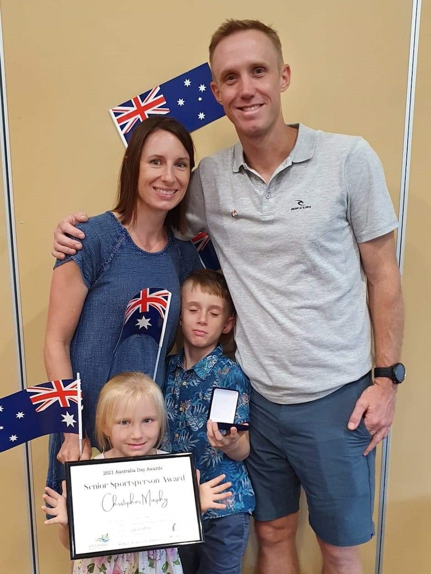 Chris Murphy, his wife, son and daughter pose for a photo with an Australian flag and certificate.