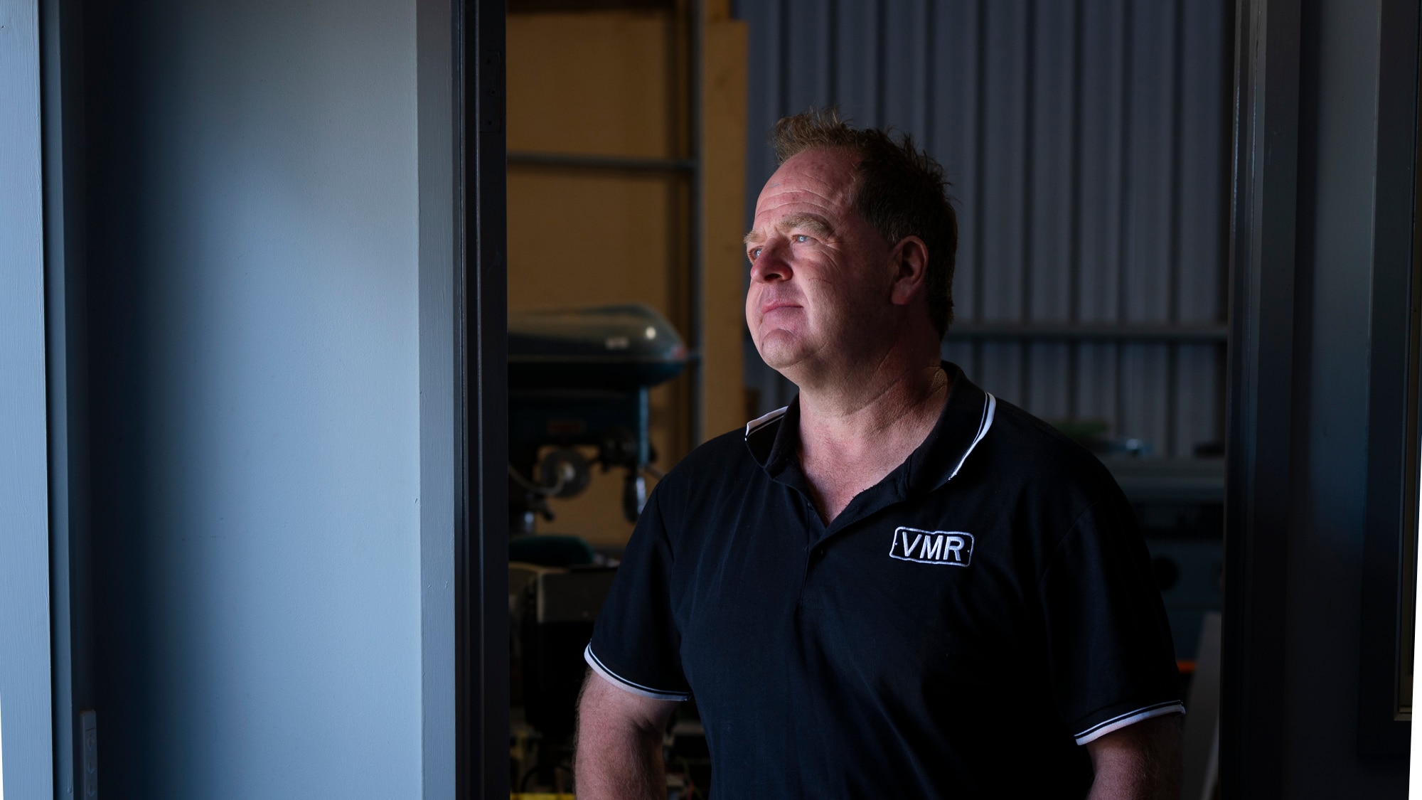 Andrew Mierisch mira por la ventana con un polo azul oscuro