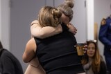 Two women hugging. Neither of their faces are visible