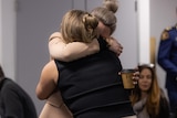 Two women hugging. Neither of their faces are visible