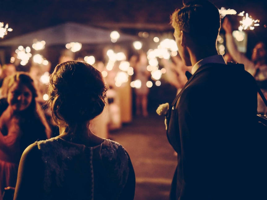 A young heterosexual couple pictured from behind on their wedding day