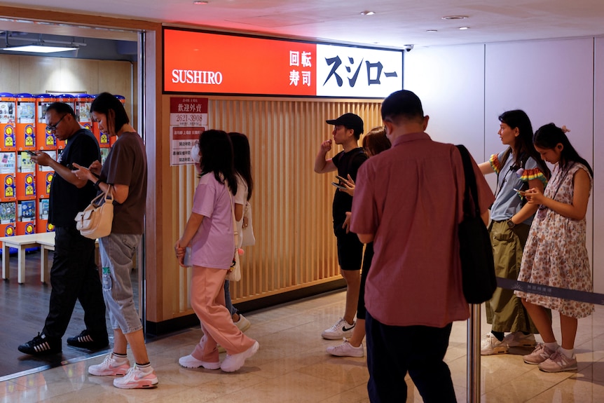 Customers queue outside of a sushi restaurant