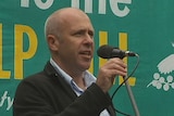 Tasmanian author Richard Flanagan in front of a Wilderness Society sign.