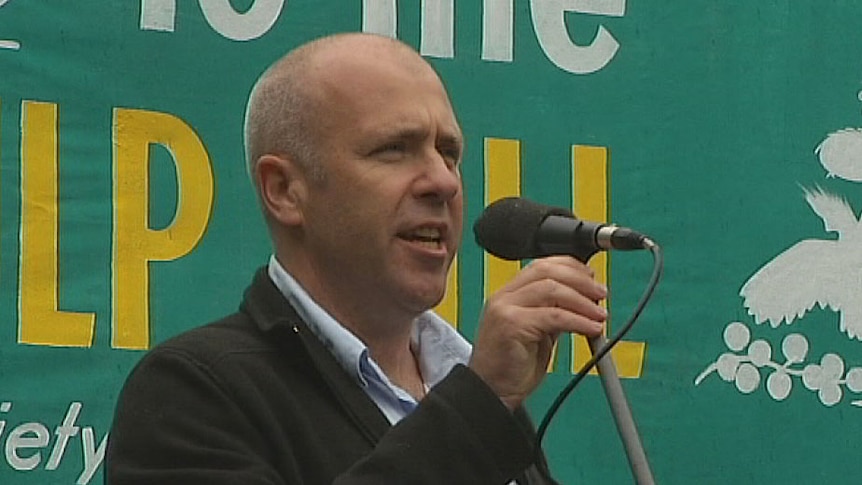 Tasmanian author Richard Flanagan in front of a Wilderness Society sign.