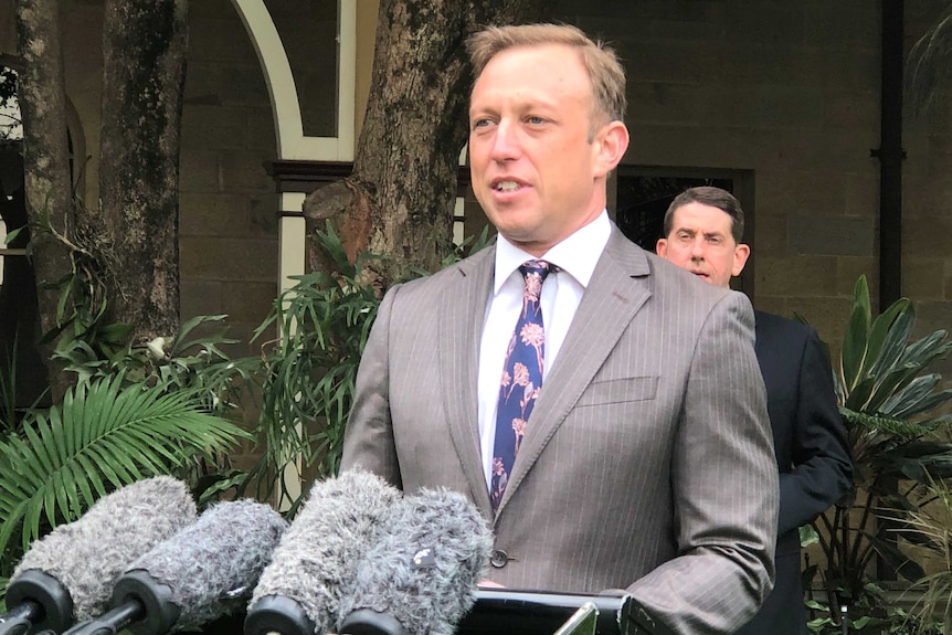 Steven Miles at a press conference podium in front of microphones.