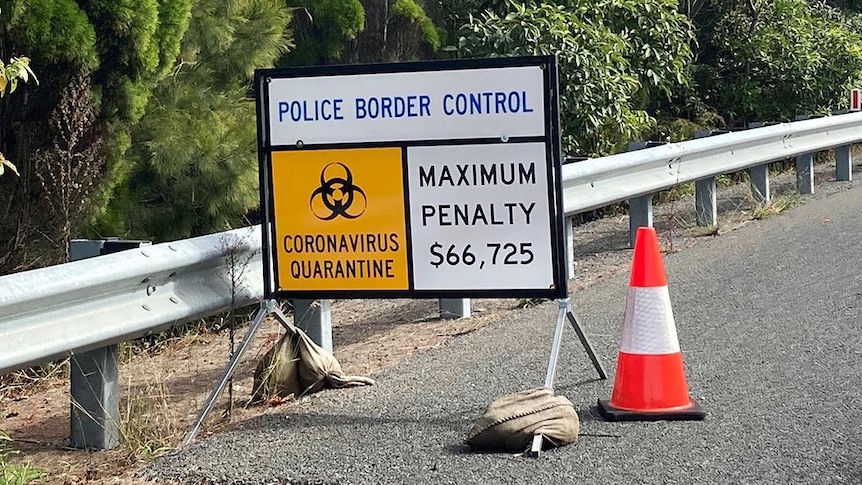 Police border control road sign reading coronavirus quarantine and maximum penalty $66,725.