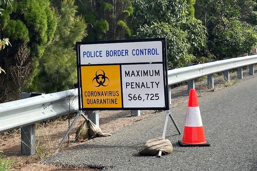 Police border control road sign reading coronavirus quarantine and maximum penalty $66,725.