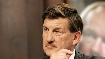 Former Victorian premier Jeff Kennett wears a pinstripe suit and moustache and looks to the left