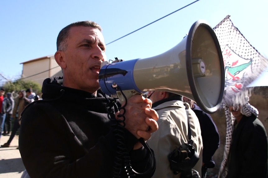 Community leader Muard Shtaiwi yells in his megaphone as the people of Kafr Qaddum gather for their weekly protest.