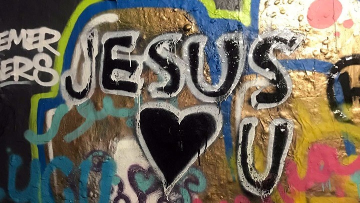 A bright graffiti wall shows the words "Jesus loves you"