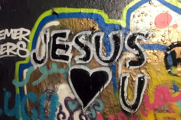 A bright graffiti wall shows the words "Jesus loves you"