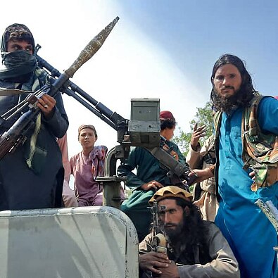 Three armed Taliban fighters sit in a vehicle