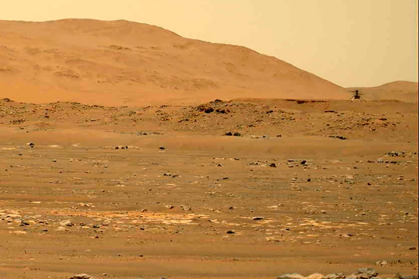 Un helicóptero negro aparece a la derecha desde lejos, flanqueado por un paisaje marciano.