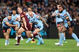 Queensland skipper Daly Cherry-Evans runs, holding the ball to his chest, while NSW players are caught on the back foot.