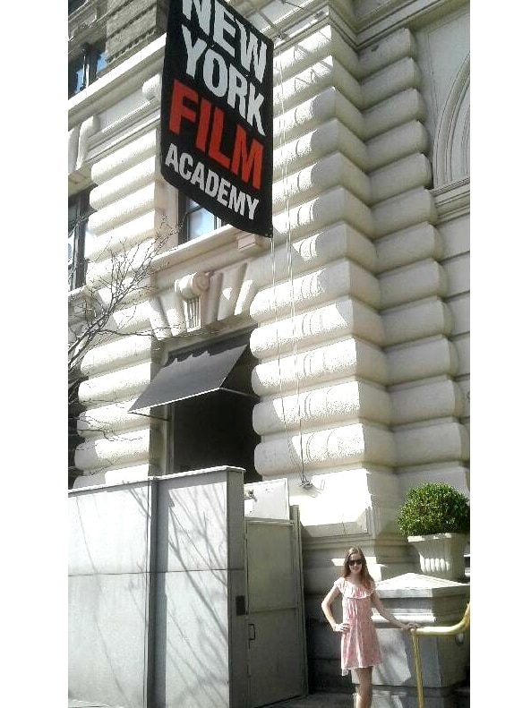 Portrait photo showing scale of large building with a small girl at the bottom. She is smiling and standing.