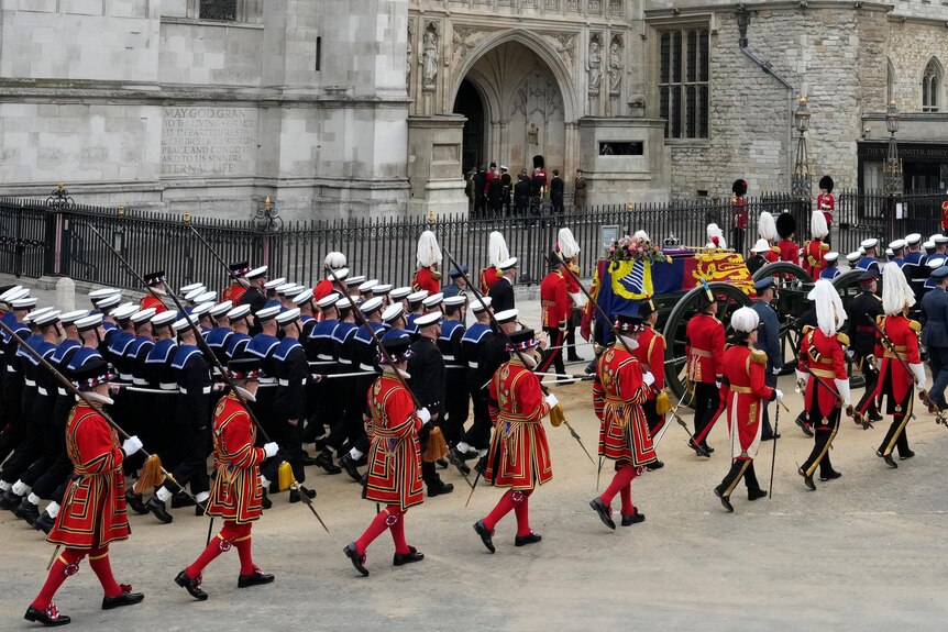 A procession of military lead the Queen's coffin 