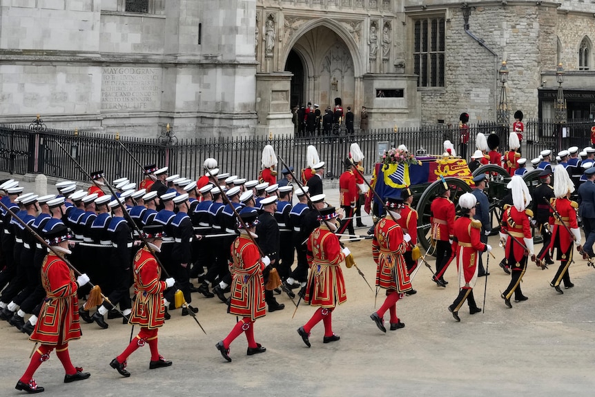 A procession of military lead the Queen's coffin 