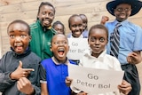 a group of students in uniform hold up a 'go peter bol' sign