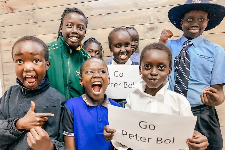 a group of students in uniform hold up a 'go peter bol' sign