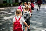 Students line up behind each other in the playground in an article about preparing children for starting school.