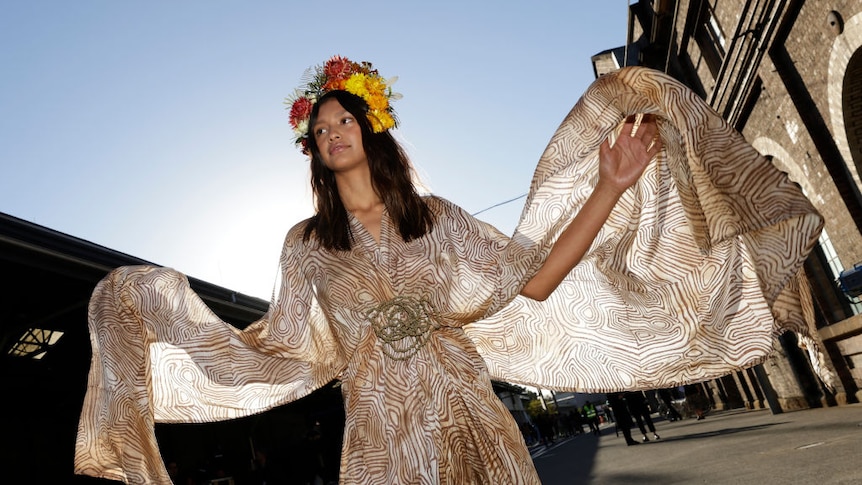 Indigenous dancer with flowers in her hair and a beautiful flowing dress on out the front of Carriageworks in Redfern