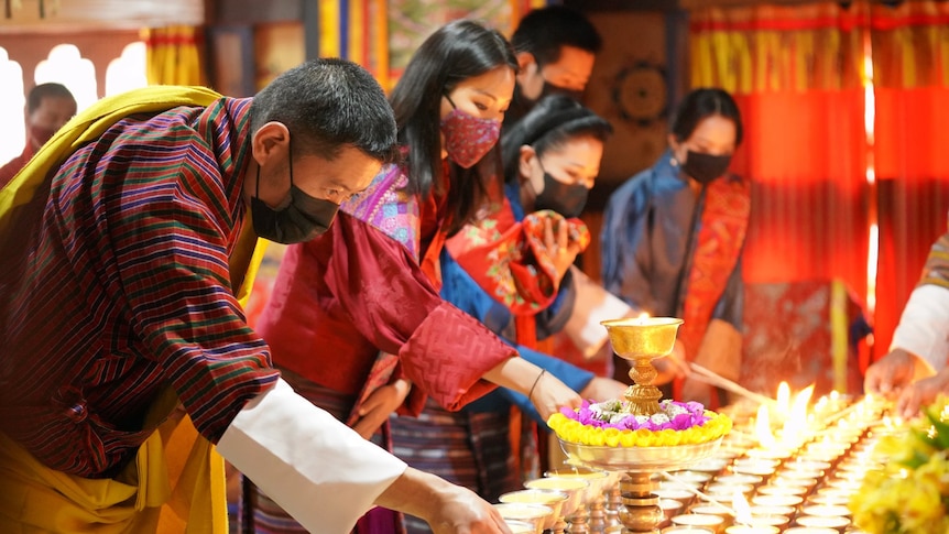 A row of Bhutanese people lighting candles 