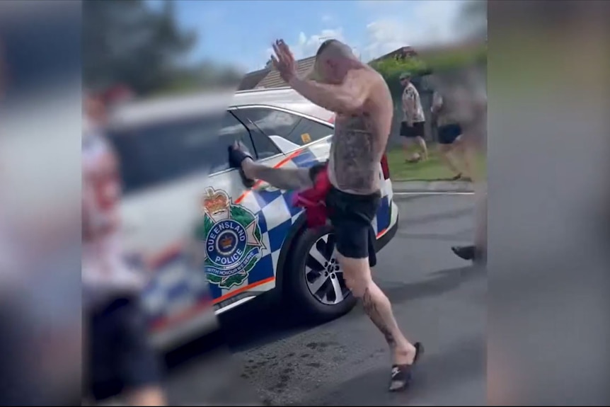 A man seen on video kicking a police car 