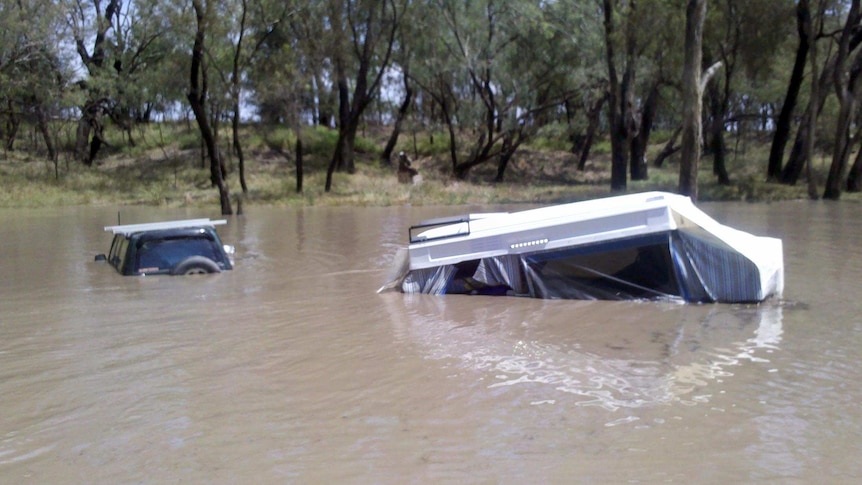 Floodwaters cover a car and caravan that had been camped next to the Condamine River.